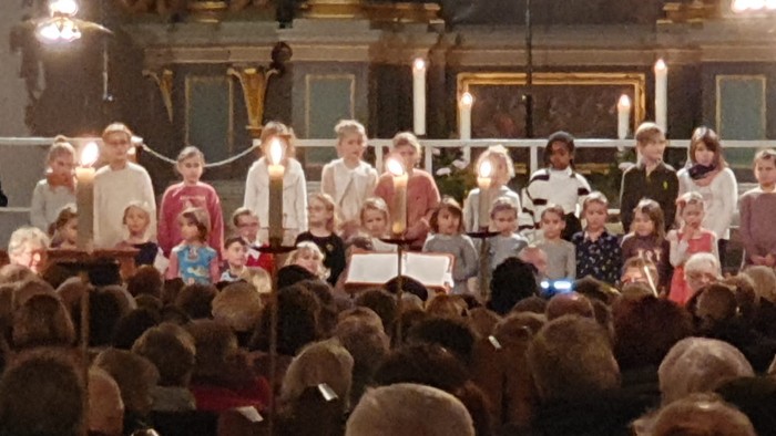 Eine Gruppe von Menschen steht auf einer Bühne und singt in einer Kirche.