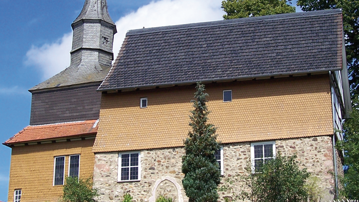 Das Bild zeigt ein altes, gelbes Gebäude mit einem Turm und einem steilen Dach.