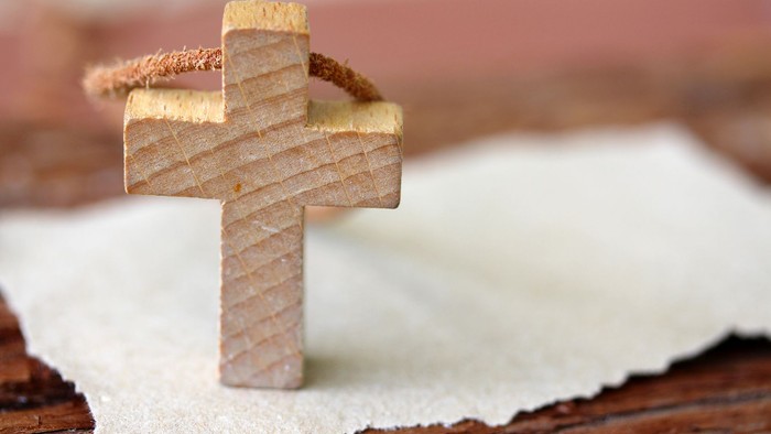 Ein hölzernes Kreuz liegt auf einem weißen Tuch.
