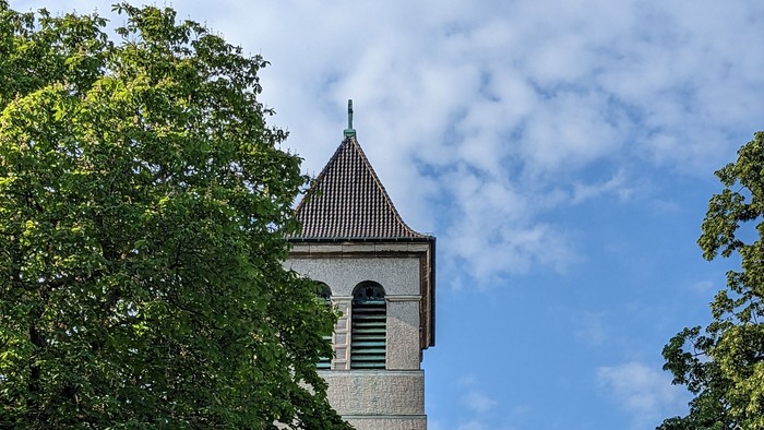 Turm mit Uhrwerk zwischen Bäumen