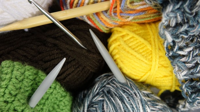 Bunte Wolle, Stricknadeln und fertige Strickstücke