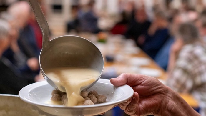En person serverer grøngrød med nødder fra en kælder til en bolle.