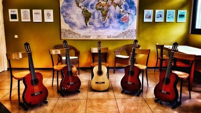 Mehrere Gitarren stehen vor einer Weltkarte und Stühlen