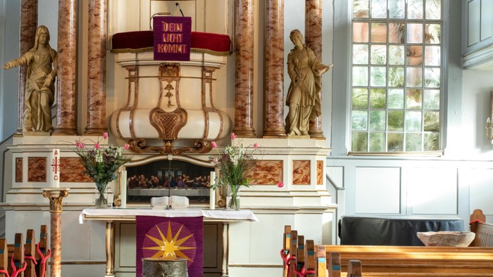 Innenraum einer Kirche mit Altar, Statuen und Blumen.