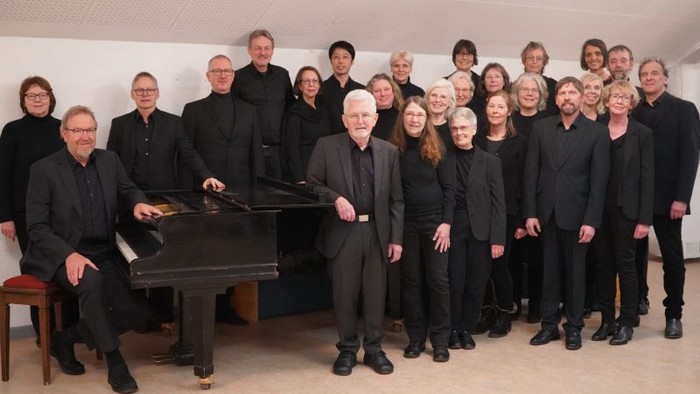 Gruppe von Musikern, die mit einem Klavier posieren.