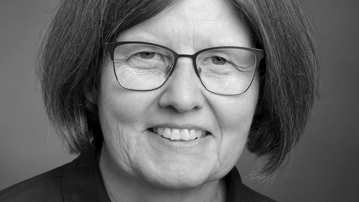 En svart-hvid portrætfoto af en kvinde med kort hår og briller.