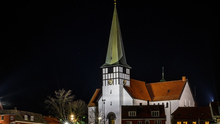 En kirke med tårn og et skip i vandet ved nat