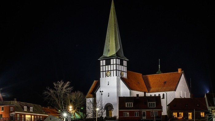 En kirke med tårn og et skip i vandet ved nat