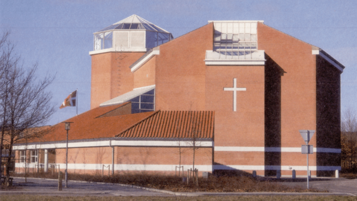 En stor, rød kirke med et stort kors på fasaden og en tårnagtig struktur på taket