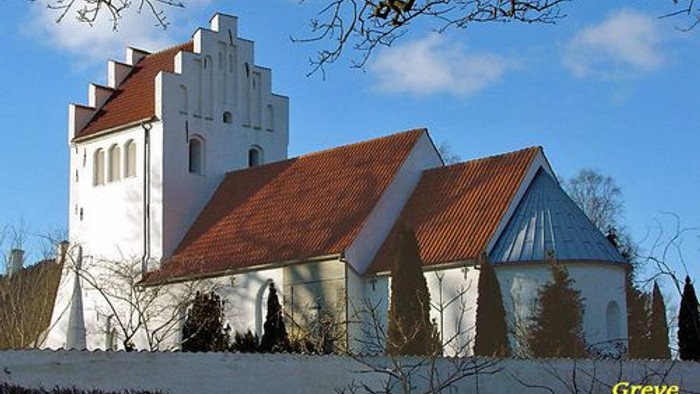 Et hvidt kirkebygning med røde tag og en klokketårn i en snedækked landskab