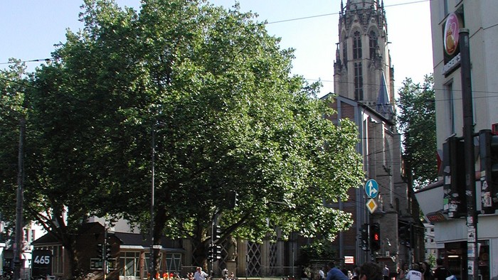 Frau wartet an belebter Straßenecke auf Grünlicht