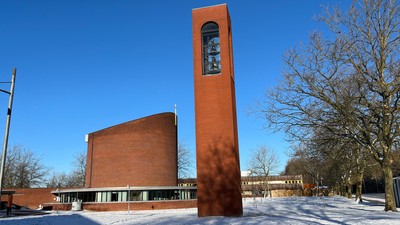 En rød murstenskirke med klokketårn og snedækket jorden foran