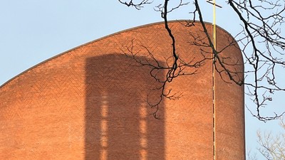 Det er et stort rødt murstensbygning med en lang skygge.