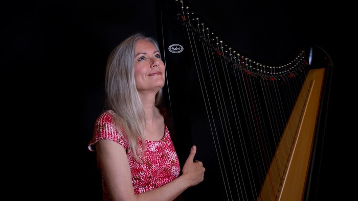 Kvinde i rød kjole, der spiller harpe.