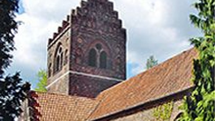 Et gammelt teglsteinshus med en tårnagtig struktur og bægerformede vinduer.