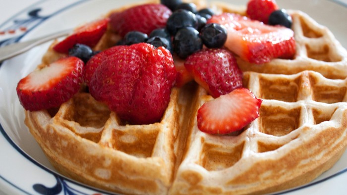 Ein Waffel mit frischen Erdbeeren und Blaubeeren auf einem Teller