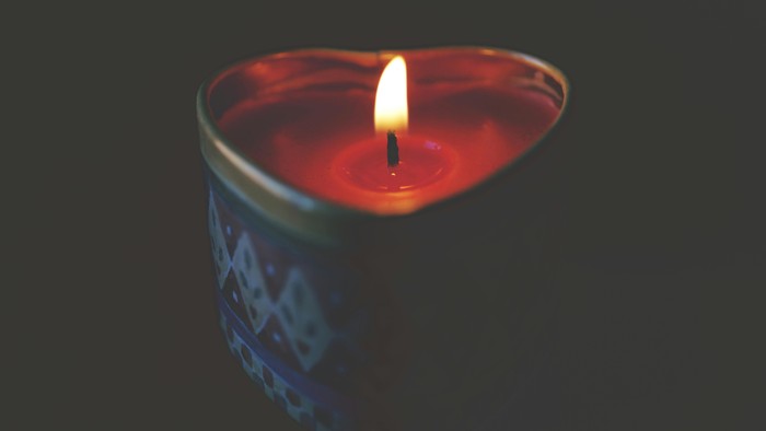 Et tændt stearinlys i en rød glaslygter med blå mønstre.