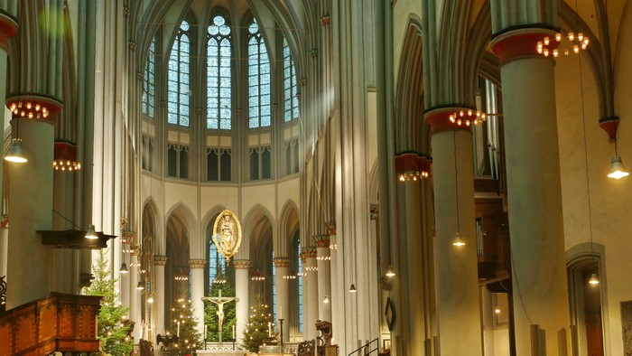 Großer Kathedraleninnenraum mit hohen Decken, Buntglasfenstern und aufwendigen Verzierungen.