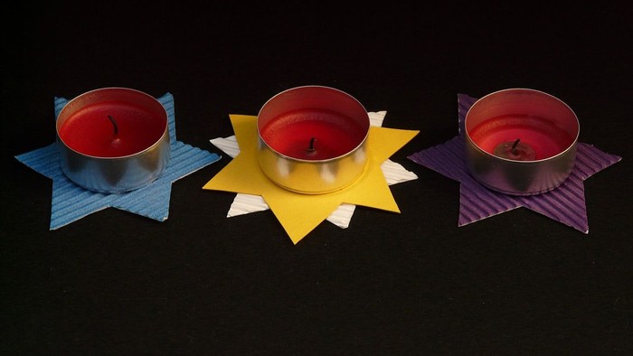 Drei Kerzen in Sternform auf schwarzem Hintergrund