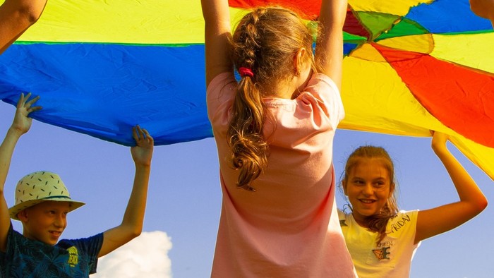 Kinder spielen mit einem bunten Tuch im Freien