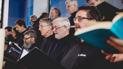 Eine Gruppe von Männern mit Laptops und Büchern in einem Raum.