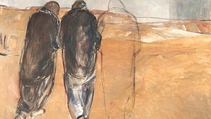 Zwei Personen gehen in einer sandigen Landschaft, eine dritte Person ist verschwommen.