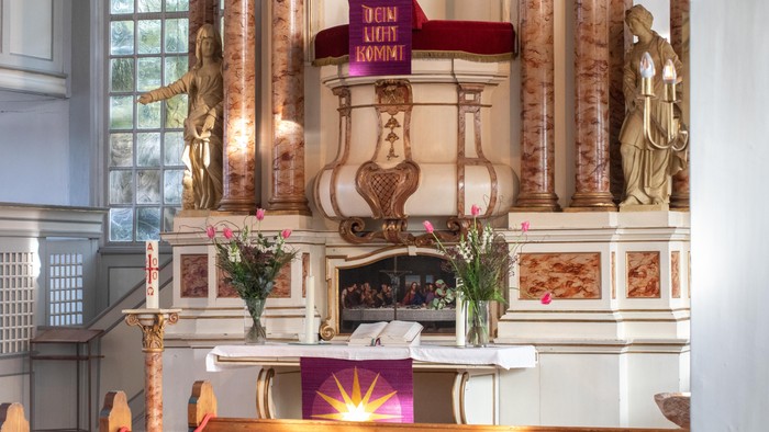 Ein Altar in einer Kirche mit zwei Blumensträußen und einer Bibel.