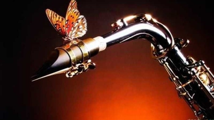 En saxofon med en farverig sommerfugl på mundstykket