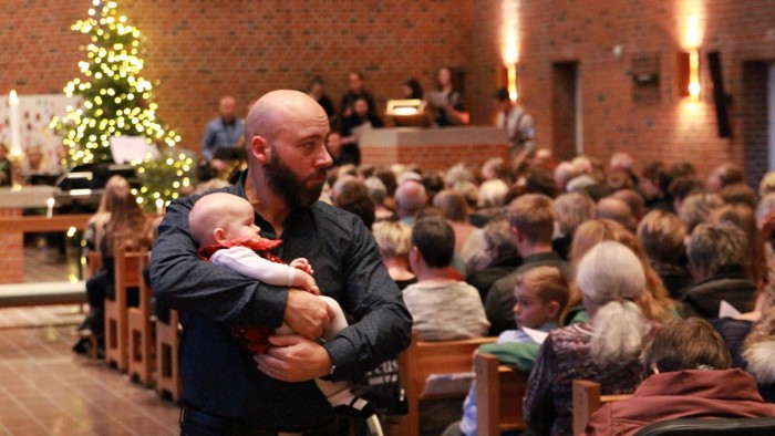 En mand holder et barn i en kirke.