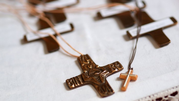 Mehrere hölzerne Kreuze mit Schnüren auf weißem Stoff