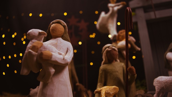 En julekrybbe med several figurer, herunder en kvinde med barn og en mand med stav.