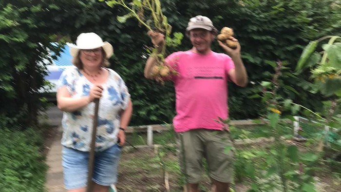 Zwei Personen im Garten halten Gemüse.