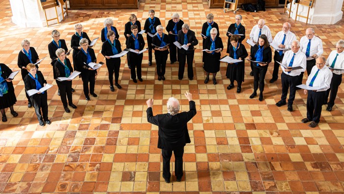En gruppe mænd i formelle klæder står i en hal og poserer til en foto