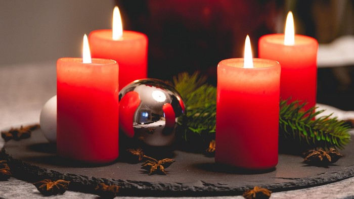 Vier brennende, rote Kerzen auf einem Adventsteller