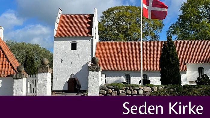 Et hvidt og rødt kirkebygning med en dansk flag på tårnet