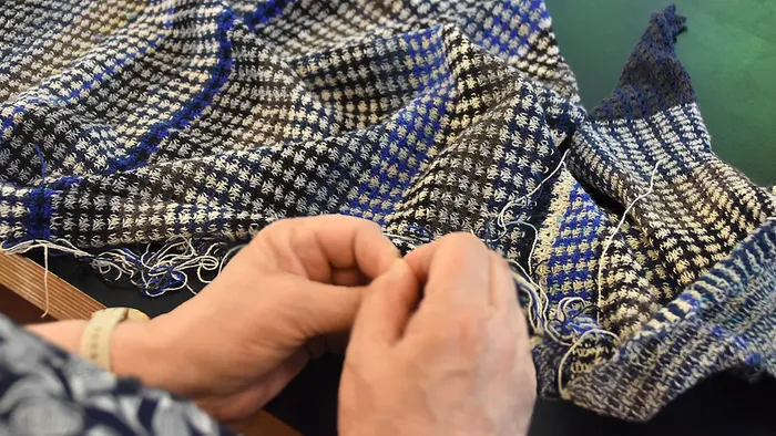 Dame samler den strikkede letvægtssjal sammen med nål og tråd