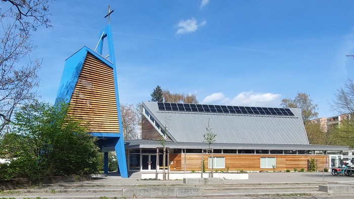 Moderne Kirche mit blauem Turm und Solarpanels auf dem Dach