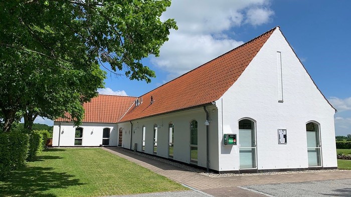 Hvid bygning med rødt tag og græsplæne