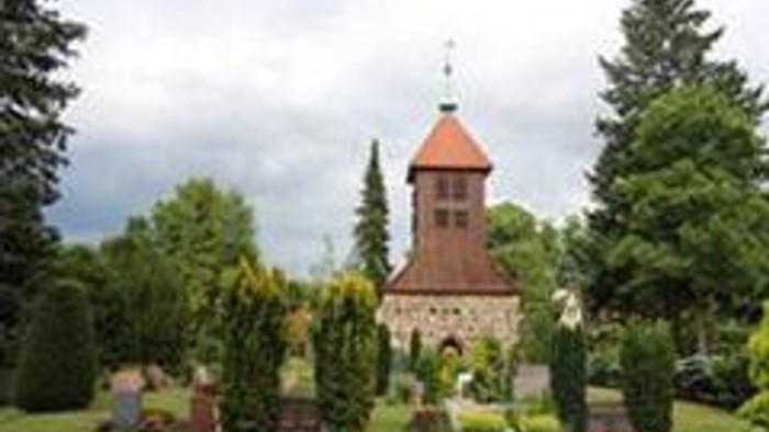 Ein rotes Backsteingebäude mit einem Turm, umgeben von grünem Gras und Bäumen.