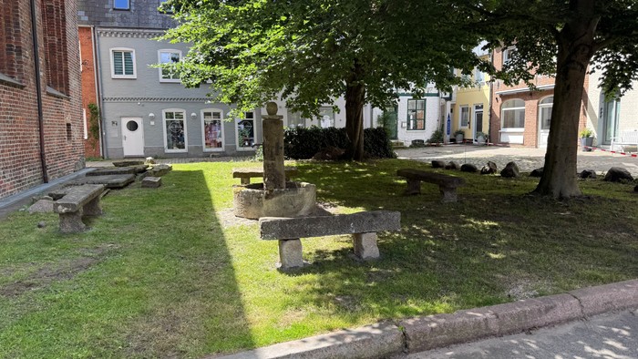 Ein kleiner Park mit Bänken und Bäumen vor Häusern.