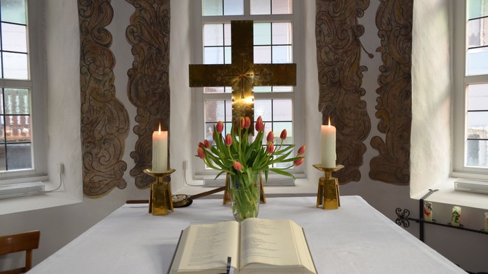 Kirchenaltar mit offenem Buch, Kerzen und Blumenarrangement