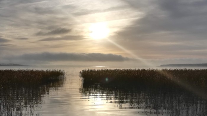 En rolig sø med solgang og klodebælte