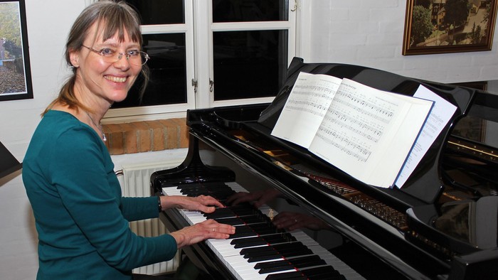 Kvinde spiller piano i stue