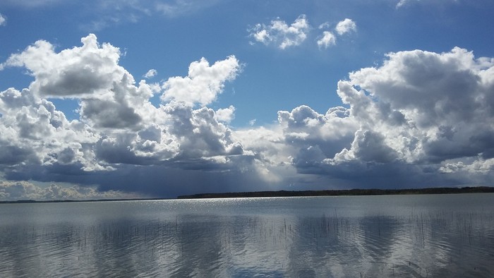 Stille sø under dramatiske, luftige skyer med et strejf af kommende regn.