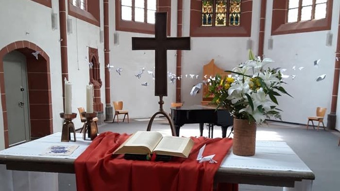 Kirchenaltar mit Kreuz, Blumen und aufgeschlagenem Buch