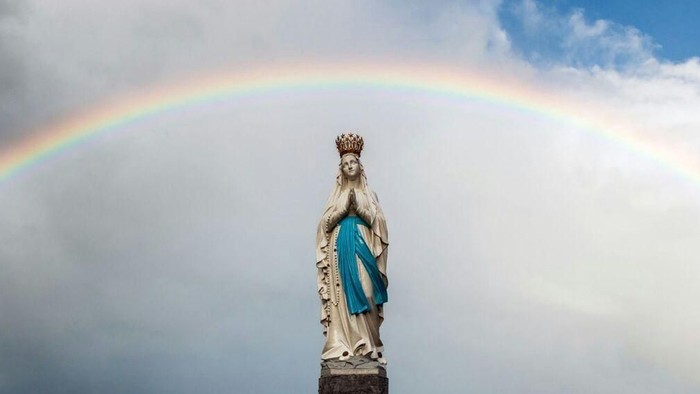 Eine Statue einer Frau mit einem Regenbogen im Hintergrund