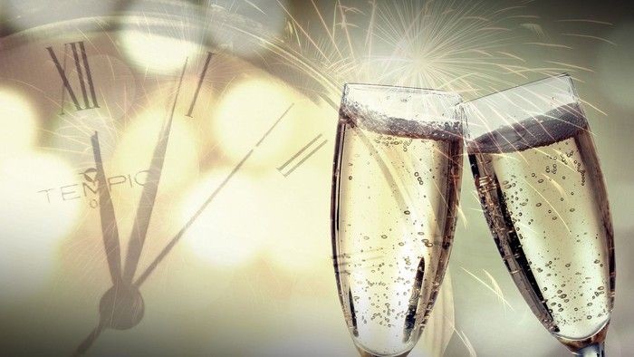 to champagneglas der klinger mod hinanden og et ur i baggrunden der indikerer at det nye år er her.