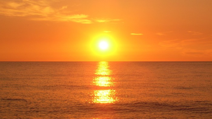 Solset over havet med gule og orange farver