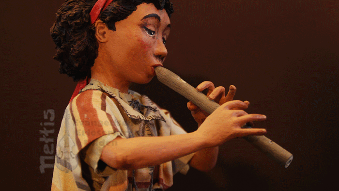 Eine Puppe spielt eine Flöte und trägt ein traditionelles Kleid.