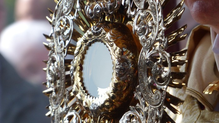 Eine goldene, verzierte Monstranz wird von einer Person gehalten